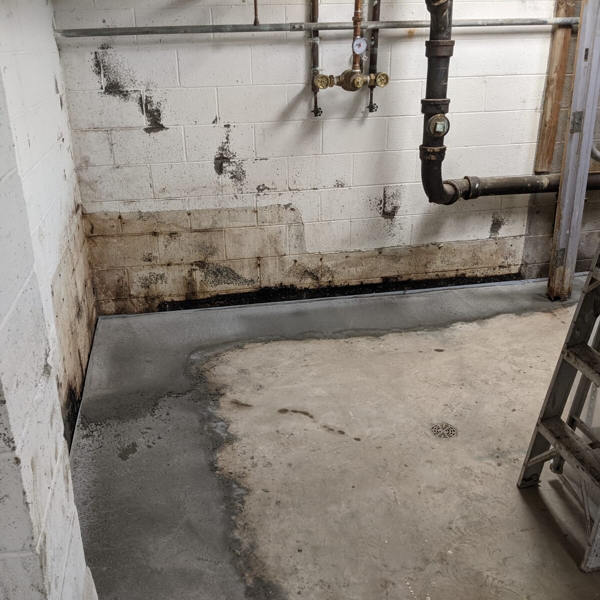 This photo was taken shortly after the initial work was completed for waterproofing. Visible are the non-painted areas of concrete where prior concrete structure/barrier was installed in a (failed) attempt to divert water intrusion. Also visible is the poor state of the walls prior to crack repair. Northwest Basement Corner in January 2021