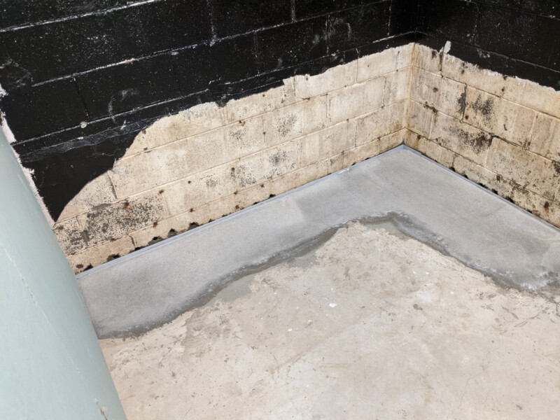 New concrete pour. The portion of concrete barrier removed is exceptionally visible here. In the snack shack room (and the east wall in general), an alternate product "liquid rubber" was used to help seal out moisture intrusion. This portion of the basement is/was particularly problematic. New Concrete in Snack Shack Storage (Southeast Corner) in January 2021