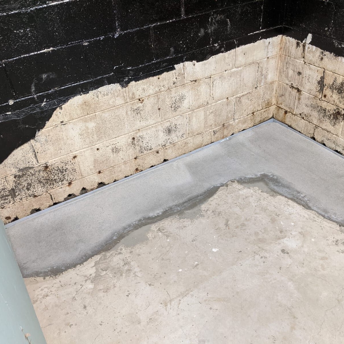 New concrete pour. The portion of concrete barrier removed is exceptionally visible here. In the snack shack room (and the east wall in general), an alternate product "liquid rubber" was used to help seal out moisture intrusion. This portion of the basement is/was particularly problematic. New Concrete in Snack Shack Storage (Southeast Corner) in January 2021
