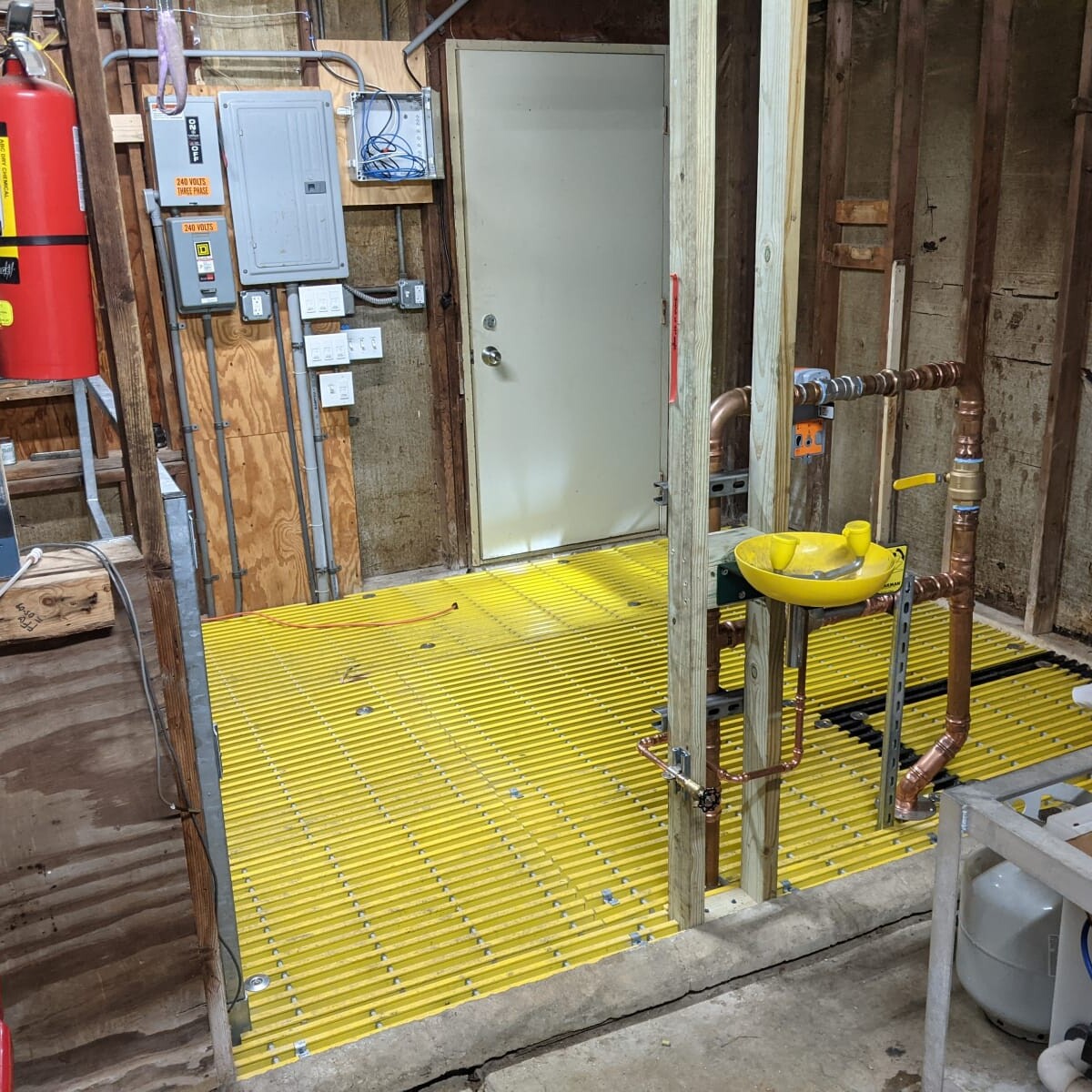 A view of the new floor (and piping, with eye wash) from the concrete floor side of the pump house on January 11th, 2021. New Floor (Alternate View)