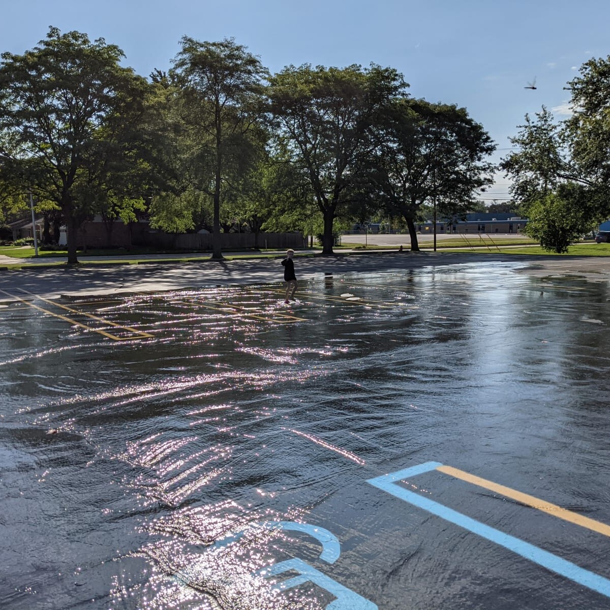 A tremendous amount of water from the pool is being pumped out onto the parking lot, eventually ending up in the sewer. Flooded Parking Lot