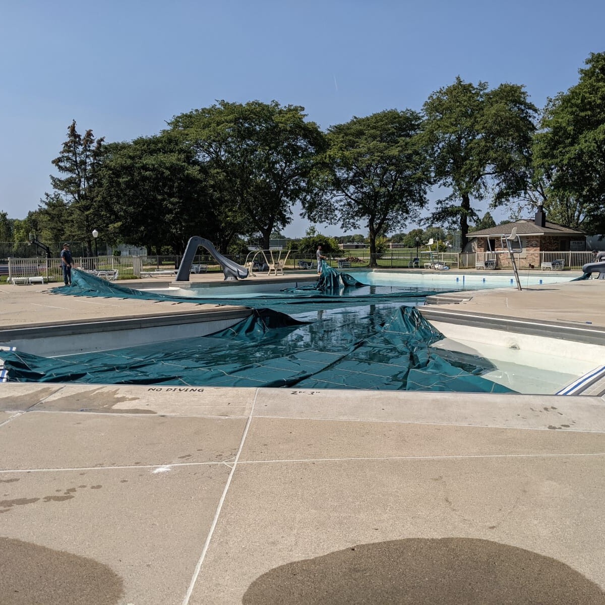 The cover is being pulled onto the pool. Covering the Pool (1 of 2)