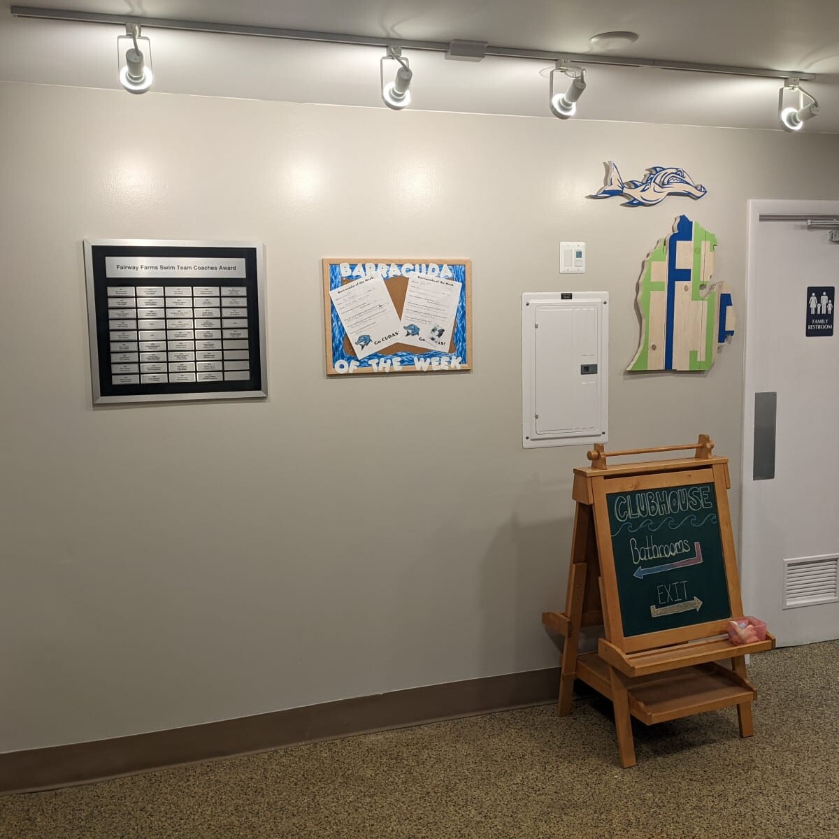 A view of the plaques, signs, etc., mounted to the east wall in the lobby (along with the newly repainted electrical panel). Taken on July 11th, 2022. East Wall Signs